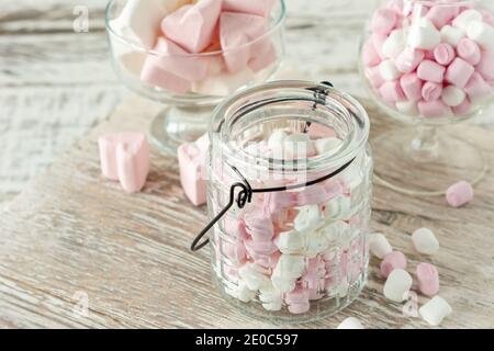 Assortiment de guimauves roses et blanches dans des tasses en verre sur fond de bois. Guimauve en forme de coeur pour chocolat chaud ou cacao. Banque D'Images