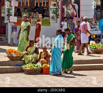 INDE MADURAI TAMIL NADU MEENAKSHI AMMAN TEMPLE VENDEURS DE FRUITS COMPLEXES ET LES SARIS COLORÉS OU SAREES À L'EXTÉRIEUR DES TEMPLES Banque D'Images