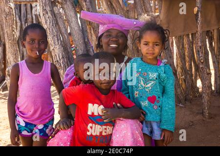 Herero femme entourée de ses enfants en Namibie, en Afrique, elle porte le chapeau ou le casque traditionnel en forme de corne, concept de peuple africain Banque D'Images