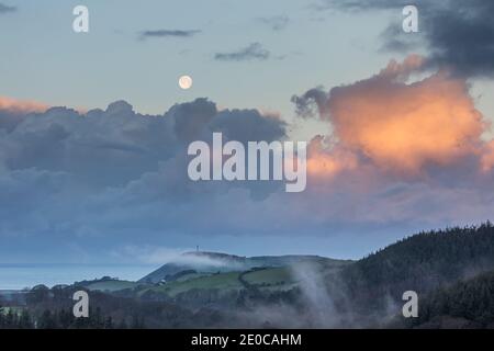 Aberystwyth, Ceredigion, pays de Galles, Royaume-Uni. 31 décembre 2020 Royaume-Uni Météo: Une matinée froide à Aberystwyth alors que la dernière pleine lune en 2020 commence à s'établir, avec le lever du soleil éclairant les zones de la basse couche de nuages au-dessus du monument Pendinas. Tandis que la température chute à moins 1 degré ce matin sur la côte ouest. © Ian Jones/Alamy Live News Banque D'Images