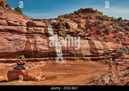 Randonneurs en cascade, Keet Seel Canyon à Skeleton Mesa, sur la piste des ruines de Keet Seel au monument national Navajo, Shonto plateau, Arizona, États-Unis Banque D'Images