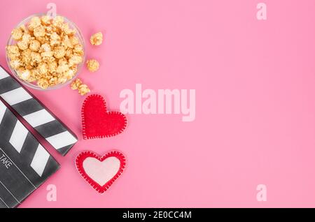 Concept de film de la Saint-Valentin. Papperboard de cinéma avec coeurs et pop-corn caramel avec espace pour les copies sur fond rose. Banque D'Images