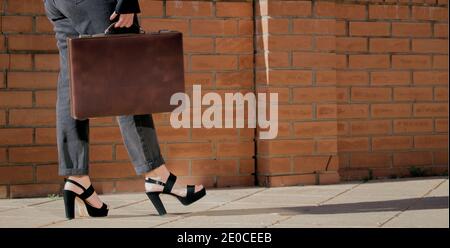 Gros plan sur les jambes de femme élégantes et méconnues dans un pantalon et des talons noirs, marche avec un porte-documents dans sa main, Girl Boss concept 2021. Banque D'Images