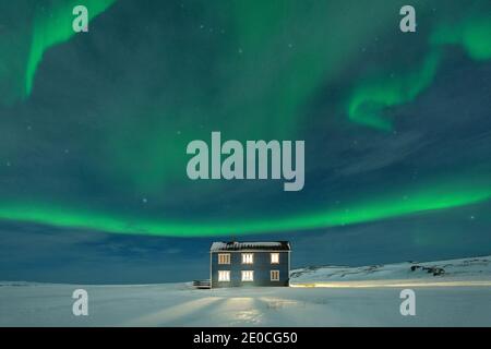 Aurores boréales (Aurora borealis) sur la maison illuminée dans la neige, Veines, Kongsfjord, Varanger Peninsula, Finnmark, Norvège, Scandinavie Banque D'Images