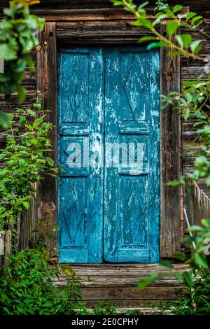 Ancienne porte bleue surcultivée détruite d'une maison en bois dans un village Banque D'Images