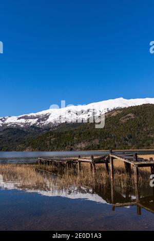 Vue sur la scène de l'ancienne jetée en bois contre les montagnes enneigées des Andes dans le lac vert (Lago Verde) dans le parc national de Los Alerces, Patagonia, Argentine Banque D'Images