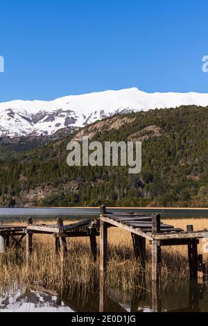 Vue sur la scène de l'ancienne jetée en bois contre les montagnes enneigées des Andes dans le lac vert (Lago Verde) dans le parc national de Los Alerces, Patagonia, Argentine Banque D'Images