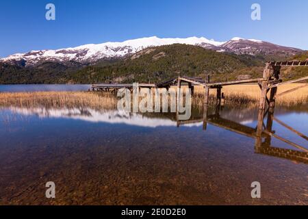 Vue sur la scène de l'ancienne jetée en bois contre les montagnes enneigées des Andes dans le lac vert (Lago Verde) dans le parc national de Los Alerces, Patagonia, Argentine Banque D'Images