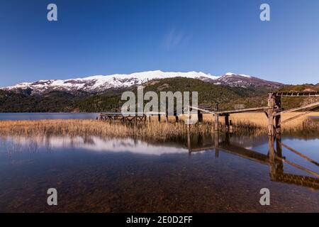 Vue sur la scène de l'ancienne jetée en bois contre les montagnes enneigées des Andes dans le lac vert (Lago Verde) dans le parc national de Los Alerces, Patagonia, Argentine Banque D'Images