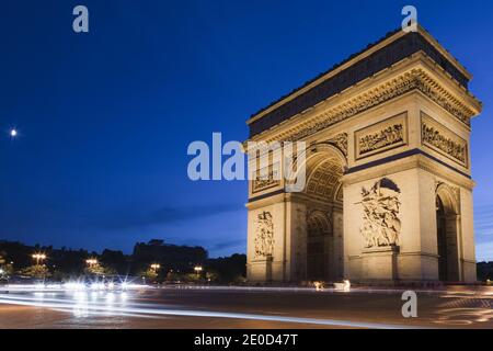 Des sentiers de lumière sont laissés à l'arrière de la circulation automobile animée autour de l'Arc dr Triomphe de nuit à Paris, France Banque D'Images