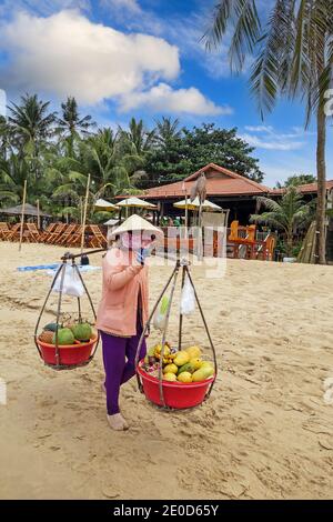 Une femme portant un chapeau conique traditionnel, appelé un non la, vendant des fruits sur la plage à Phu Quoc, Vietnam, Asie Banque D'Images