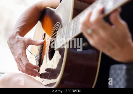 Mains de femme jouant de la guitare acoustique. Concentrez-vous sur les doigts guitaristes à côté du trou sonore. Leçons de musique, concepts de pratique Banque D'Images