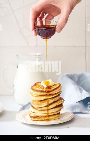 Verser du miel sur une pile de crêpes moelleuses pour le petit déjeuner avec baies et beurre Banque D'Images