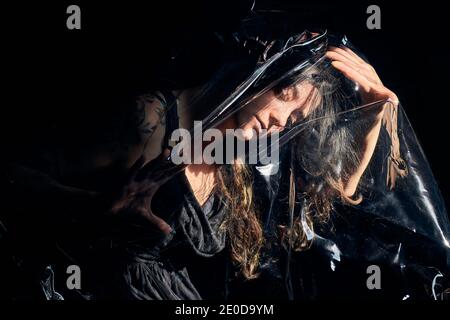 Par le dessus de la femelle couché sur fond noir sous la feuille de cellophane et de montrer le concept de pollution plastique Banque D'Images
