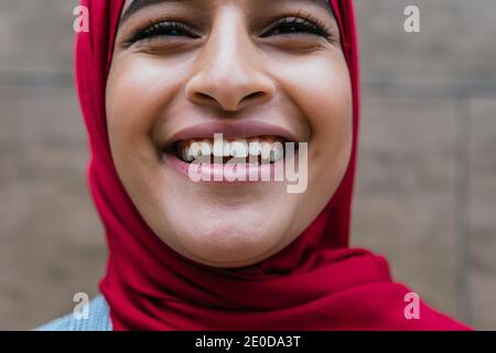 Crop optimiste femme arabe portant un foulard debout sur la rue et riant avec joie tout en regardant vers l'avenir Banque D'Images