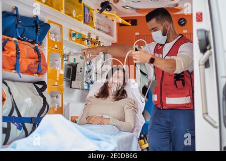 Paramédical mettant le masque du ventilateur au patient allongé sur une civière médicale en ambulance Banque D'Images