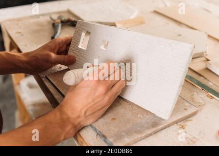 Un artisan méconnaissable utilisant un outil et créant un mur de construction miniature du plâtre dans l'atelier d'art Banque D'Images