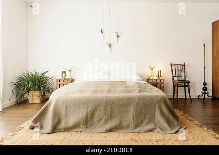 Chambre lumineuse avec intérieur minimaliste, lit confortable et bois mobilier avec décoration boho sur mur blanc Banque D'Images