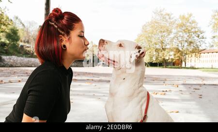 Jeune femme asiatique propriétaire embrassant l'américain Pit Bull, obéissant et purébré Chien Terrier Banque D'Images