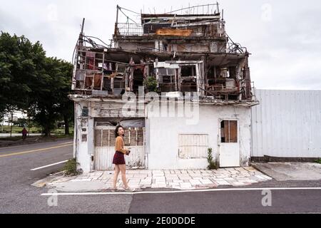 Vue latérale d'une femme se tenant dans la rue près de Shabby Old Bâtiment situé sur la côte est Banque D'Images