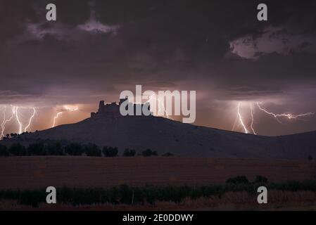 Vue imprenable sur le ciel sombre d'orage avec des éclairs lumineux saisissants au-dessus de la forteresse en pierre sur la colline dans les montagnes Banque D'Images