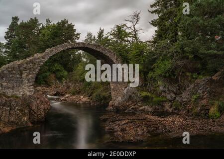Paysage du pont à cheval Old Pack au-dessus de rivière calme en dessous Ciel nuageux en Écosse Banque D'Images