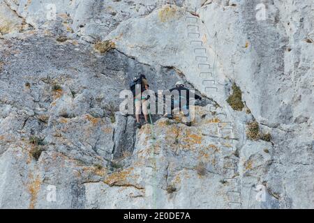 Vue arrière de braves grimpeurs méconnaissables pente rocheuse abrupte tout en pratiquant l'escalade ensemble sur un terrain montagneux Banque D'Images