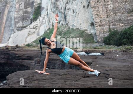 Déterminez l'équilibre de l'athlète féminin sur la planche latérale pendant les exercices pendant l'entraînement au bord de la mer Banque D'Images