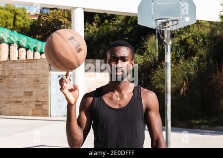 Joueur de basket-ball américain déterminé d'Afrique et de ballon d'équilibrage sur le doigt tout en regardant l'appareil photo Banque D'Images