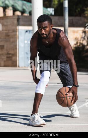 Athlète afro-américain déterminé jouant au basket-ball sur le terrain été Banque D'Images