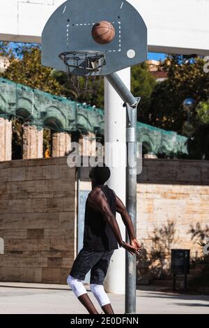 Vue arrière d'un athlète afro-américain méconnu jouant au basket-ball sur le terrain en été et en regardant la caméra Banque D'Images