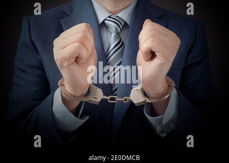 Homme d'affaires arrêté pour corruption. Homme en costume avec menottes sur les mains Banque D'Images