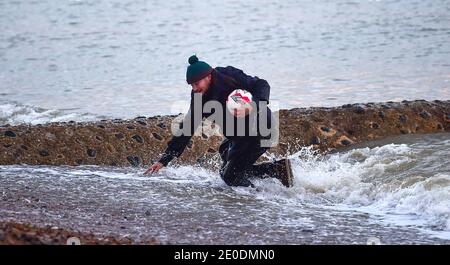 Brighton Royaume-Uni 31 décembre 2020 - ce chap se trempe alors qu'il sauve son football de la mer à Brighton Beach alors que le soleil descend sur 2020 le long de la côte sud de la Grande-Bretagne . Credit Simon Dack / Alamy Live News Banque D'Images