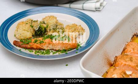 Cocotte de saumon, chou-fleur et brocoli cuits, servie avec de la ciboulette hachée sur une assiette Banque D'Images