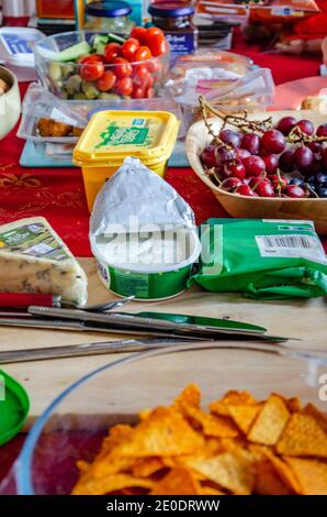 Une sélection d'aliments comprenant du fromage, des fruits et des salades de légumes disposés sur une table pour un déjeuner buffet à la maison. Banque D'Images