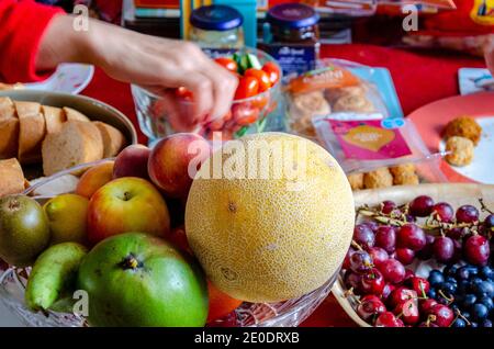 La main d'un enfant atteint pour prendre un article d'un déjeuner de style buffet qui est disposé sur une table à la maison. Banque D'Images