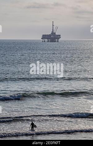 Derrick de pétrole et surfeurs au large de la côte de Huntington Beach, Orange County, Californie, États-Unis Banque D'Images