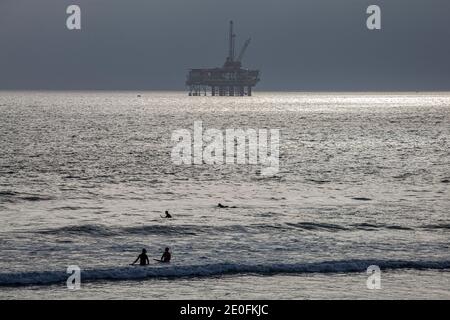 Derrick de pétrole et surfeurs au large de la côte de Huntington Beach, Orange County, Californie, États-Unis Banque D'Images