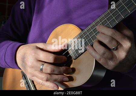 Femme jouant un ténor ukulele à 5 cordes, section médiane, foyer sélectif Banque D'Images