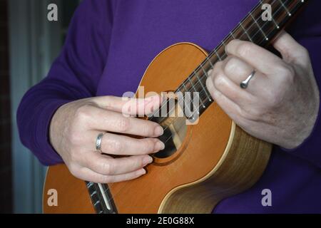 Femme jouant un ténor ukulele à 5 cordes, section médiane, foyer sélectif Banque D'Images