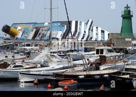 Les Vacationistes sont vus devant l'épave du paquebot de croisière cachsized Costa Concordia à l'île de Giglio, en Italie, le 20 juin, 2012.la vie dans l'île de Giglio devient normale et occupé ayant un certain nombre de touristes de partout dans le monde après la catastrophe du bateau de croisière Costa Concordia. Le paquebot de croisière de 290 mètres (951 pieds) a partiellement coulé le 12 janvier 2012 avec 3,206 passagers et 1,023 membres d'équipage à bord après avoir heurté un récif au large de la côte italienne. Le cauchemar a tué trente-deux touristes. Fait intéressant, la petite île de vacances au large de la côte de Toscane qui était peu connue à l'extérieur de t Banque D'Images