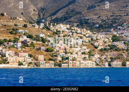 Soleil en fin d'après-midi sur les manoirs néo-classiques de Gialos et l'ancienne colline de Horio, l'île de Symi, Dodécanèse, Grèce Banque D'Images