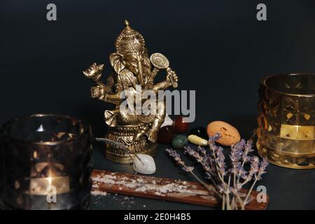 Autel occulte avec figurine de dieu Ganesha, bougies, bâton d'arôme, pierres, herbes sèches. Arrière-plan noir. Banque D'Images