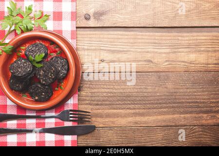 Pouding noir dans une casserole d'argile sur une base rustique en bois et une nappe à carreaux. Tapas espagnoles. Banque D'Images