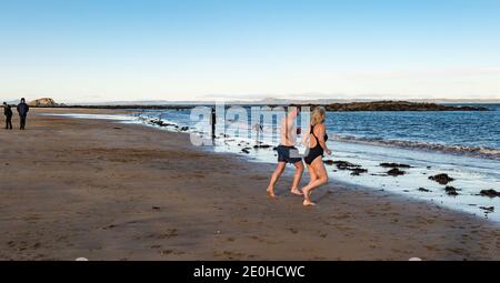 North Berwick, East Lothian, Écosse, Royaume-Uni, 1er janvier 2021. Le jour de l'an : cette année, la plage est presque vide car l'événement habituel de loony dook est annulé en raison des restrictions de Covid-19 avec seulement quelques personnes prenant un plongeon froid dans le Firth of Forth comme ce couple Banque D'Images