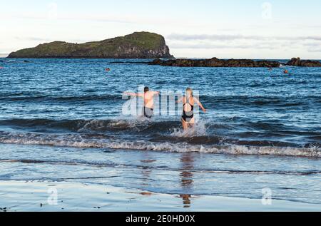 North Berwick, East Lothian, Écosse, Royaume-Uni, 1er janvier 2021. Le jour de l'an : cette année, la plage est presque vide car l'événement habituel de loony dook est annulé en raison des restrictions de Covid-19 avec seulement quelques personnes prenant un plongeon froid dans le Firth of Forth comme ce couple Banque D'Images