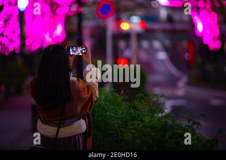 Une fille japonaise qui tourne l'éclairage dans la rue nocturne Shibuya Banque D'Images