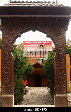 Motel et restaurant à Balvanyos, comté de Covasna, Roumanie. Entrée par une porte traditionnelle en bois sculpté avec des pigeonnets sous le toit de la porte. Banque D'Images