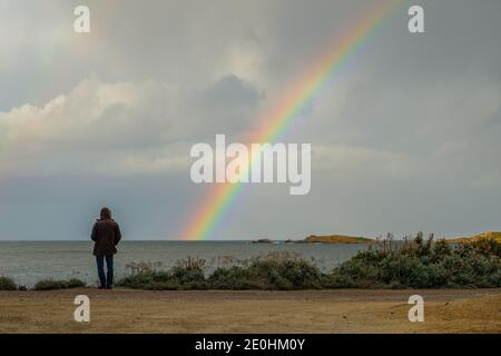 Homme en manteau à capuche avec vue sur la mer Méditerranée vers un arc-en-ciel coloré Banque D'Images