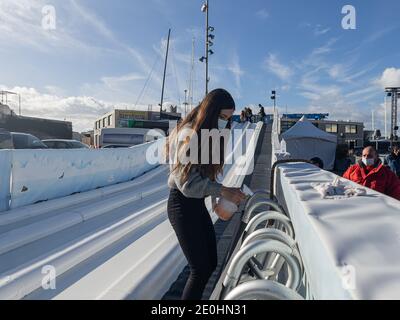 Jeune femme portant un masque médical tout en désinfectant les luges à la glissade de glace pendant la pandémie Covid-19 à Port Adriano, Majorque. Banque D'Images